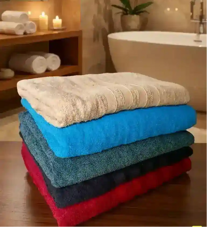 A stack of five folded towels in different colors: white, bright blue, teal, dark gray, and red, set against a plain light gray background.