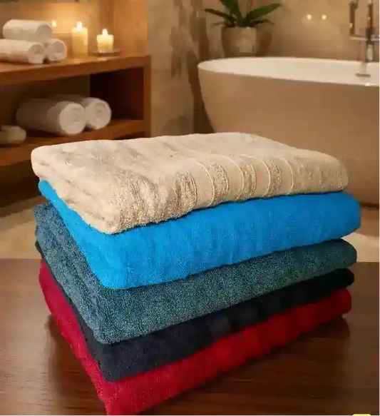 A stack of five folded towels in different colors: white, bright blue, teal, dark gray, and red, set against a plain light gray background.